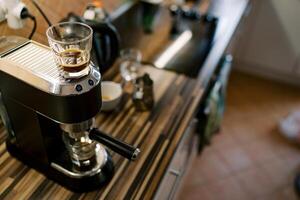 Glass of coffee stands on a carob coffee machine preparing coffee in a cup photo