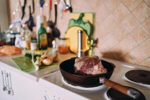 Raw roast beef is fried in a pan on the stove in the kitchen photo