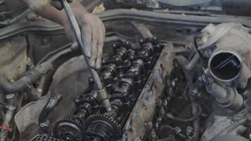 A mechanic is seen performing repairs on engine components at a car service center in a detailed view video
