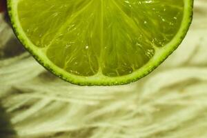 The lime is sliced in half, displaying its bright green interior. The background features a soft, neutral hue that enhances the citrus's color. photo