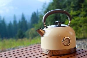 Kettle resting on wooden table with scenic mountain background during daylight photo