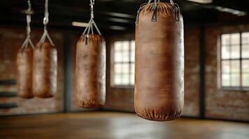 Three boxing bags hanging from the ceiling in an empty gym photo