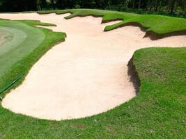 Smooth sand bunker on golf course with visible rake patterns under sunlight photo