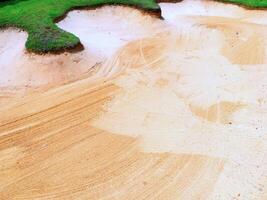 golf bunker with smooth, patterned sand surface and surrounding green grass photo