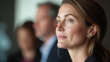 A closeup of a thoughtful woman pauses in midsentence her face candid and expressive while behind her the softly blurred silhouettes of advisors and supporters create an atmospher photo