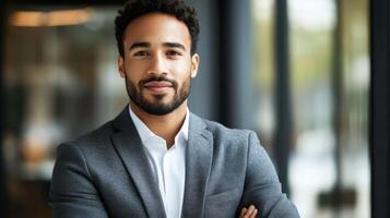 A diplomat in a charcoal gray blazer with an open expression and intentional posture presents a sense of openness while the gently blurred wall texture behind them hints at a moder photo