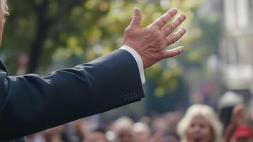 In a moment of dramatic pause the politician raises an open palm to signal the crowds attention creating a sense of unity a supporters. The medium closeup captures the fervor of thei photo