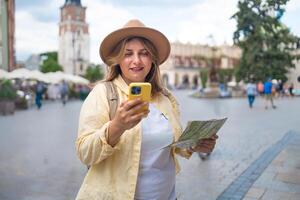Tourist woman using a phone and holding a map in a city square. photo