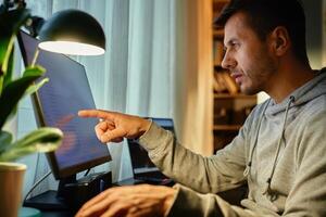 Man working remotely at desk with computer in home office photo