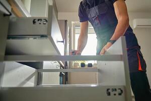 Carpenter installing and adjusting drawer front in modern kitchen photo