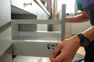Carpenter installing and adjusting drawer front in kitchen cabinet photo