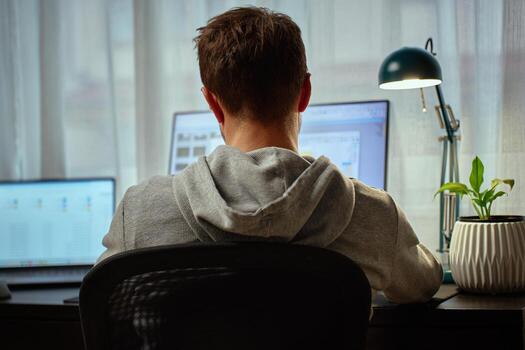 Man working from home at desk with computer and lamp photo
