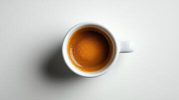 Espresso coffee in white cup sits on a plain white background. Focus is on liquid surface and creamy foam from overhead view. photo
