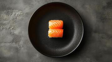 Two pieces of fresh salmon sushi stacked on a black plate. Food presentation on a dark textured background. Simple and clean aesthetic. photo