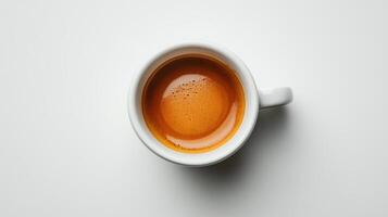 Top down view of brown espresso in a white ceramic cup on a plain white surface showcasing rich color and tiny bubbles. photo