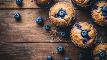 Fresh blueberry muffins on wooden table. Baked goods with berries in paper cups. Top view of sweet breakfast food. photo