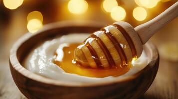 Wooden bowl with white yogurt and honey dripping from a honey dipper. Warm background with soft glowing lights. Sweet breakfast concept. photo