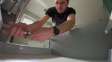 Man assembling kitchen drawer in modern cabinet using screwdriver. Handyman installing and adjusting drawer slide mechanism in contemporary kitchen. video