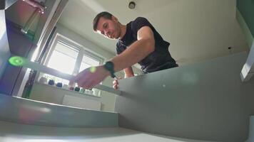Man assembling kitchen drawer in modern cabinet using screwdriver. Handyman installing and adjusting drawer slide mechanism in kitchen. Furniture installation video