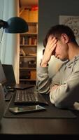 Tired man rubing eyes while working at computer. Fatigued freelancer working late at home office. Concept of stress and mental fatigue during remote work video