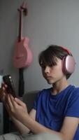 A young boy enjoys music through headphones while using his smartphone, creating a chill vibe video