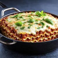 Delectable Lasagna in Dark Skillet Melted Cheese and Basil Garnish photo