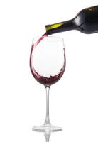 Pouring red wine into glass on white background photo