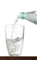 Pouring water into glass on table with isolated background photo