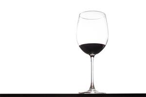 A wine glass with a red liquid inside photo