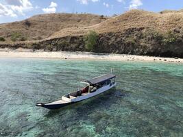 A boat on turquoise water near beach and mountain. photo