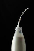 Milk in a bottle on a black background with a splash photo