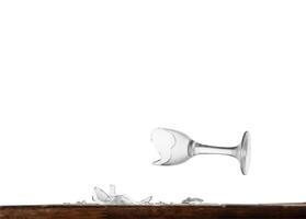 Broken wine glass on a table behind an isolated background photo