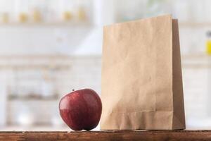 Paper bag and apple on the kitchen table photo