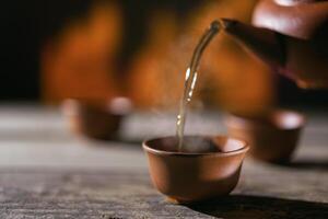 Pouring tea into a cup against the background of fire photo