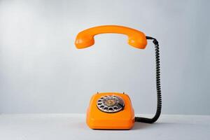An orange telephone on a white background photo
