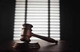 Judge's gavel on wooden table in front of blinds photo