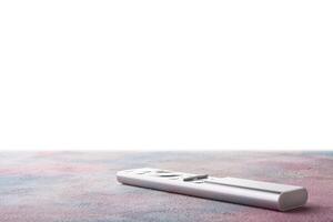 Modern metal tv remote control on table with isolated background photo