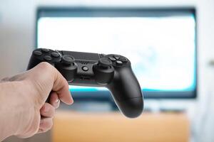 A person holding a game controller in front of a television photo