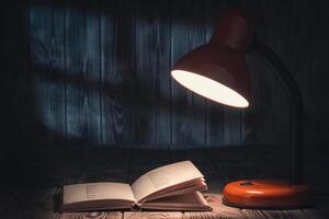 An open book and a lamp on a wooden table photo