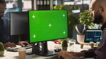 Man in office reviewing financial graphs on green screen PC, analyzing key performance indicators. Employee looking over data trends and strategic insights on chroma key computer, camera A video