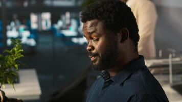Worker in office reviewing financial graphs, analyzing business performance metrics. African american employee at work looking over data trends and strategic insights, camera A video