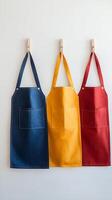 Three Linen Aprons with Pockets Hanging on Clothespins photo