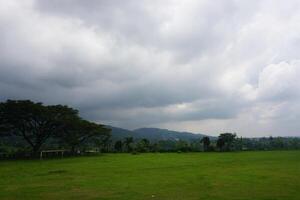 Overcast field, rural landscape, soccer goal, mountains photo