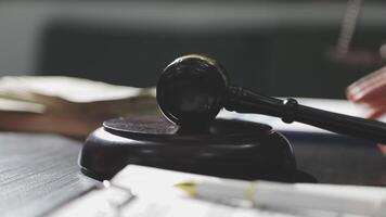 A judge's gavel on a desk with a stack of papers and money video