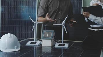 Two people standing near a table with solar panels and wind turbines video