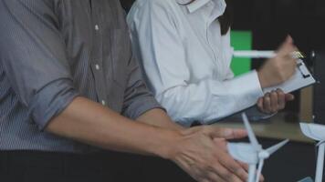Two people shaking hands while looking at a computer video