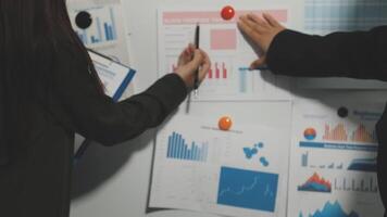 Two people pointing at graphs on a whiteboard video
