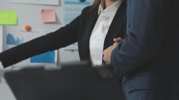 A man and woman in business attire are standing next to a laptop video