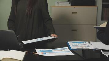 A woman is standing at a desk with a laptop and papers video