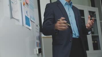 A man in a suit standing in front of a whiteboard video